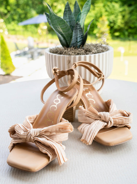 A strappy square toe, bowed heel.  The bowls made up of a textured cloth that criss crosses.  An ankle strap for extra security and a chunky heel for ease. The heel is a medium beige and the bow is a light beige.