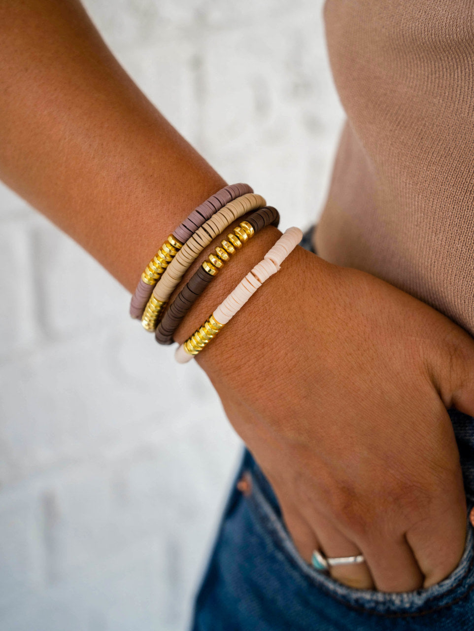 This neutral bracelet set is a stack of four.  Circular leather beads mixed in with flat gold beads.  The four bracelets consist of a light mauve, beige, brown and creme. This stack is sold together.